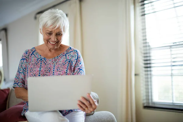 Senior vrouw met laptop in de woonkamer — Stockfoto