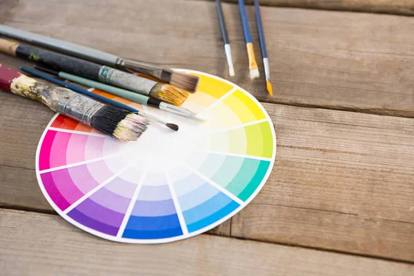 Color swatch and paintbrushes on wooden surface — Stock Photo, Image