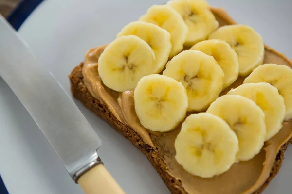 Banane affettate spalmate su pane integrale in piatto — Foto Stock