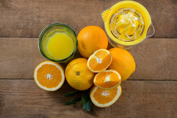 Sobretudo de laranjas com copos de suco e espremedor — Fotografia de Stock