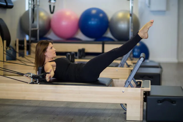 Determined woman practicing stretching exercise on reformer — Stock Photo, Image