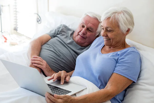 Äldre par med laptop i sovrummet — Stockfoto