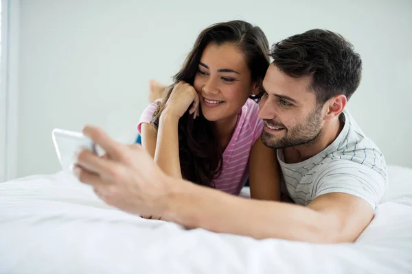 Para biorąc selfie z telefonu komórkowego w sypialni — Zdjęcie stockowe