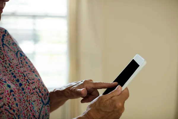 Senior kobiety za pomocą cyfrowego tabletu w salonie — Zdjęcie stockowe