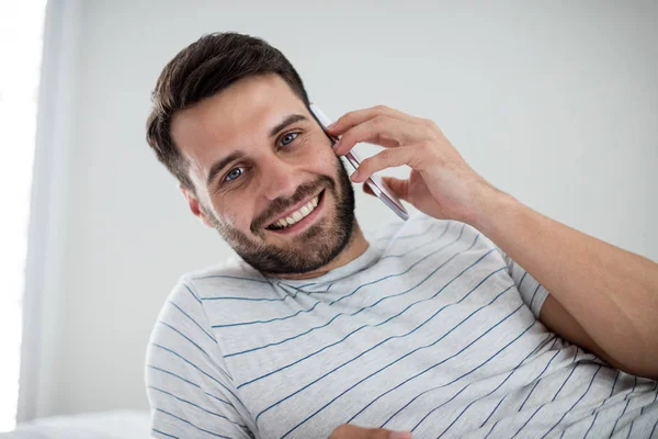 Ο άνθρωπος μιλάει στο κινητό τηλέφωνο στο υπνοδωμάτιο — Φωτογραφία Αρχείου