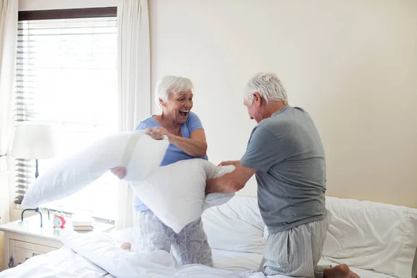 Pasangan senior bertengkar bantal di tempat tidur — Stok Foto