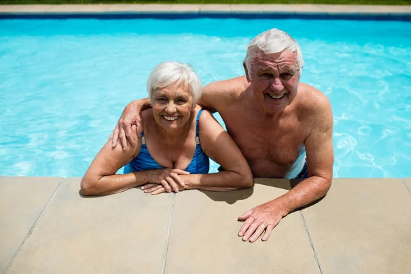 Retrato de casal sênior relaxando juntos na piscina — Fotografia de Stock