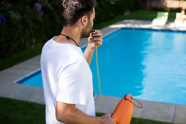 Lifeguard blowing whistle at poolside — Stock Photo, Image