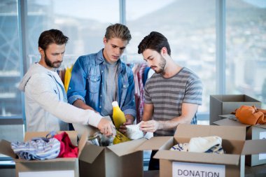 Creative business team sorting clothes in donation box clipart