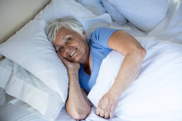Пожилая женщина расслабляется в спальне — стоковое фото