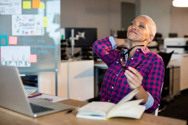 Tired creative businesswoman sitting on desk — Stock Photo, Image