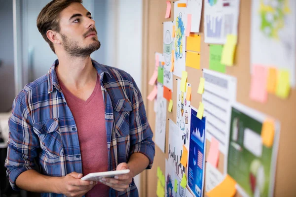 Man met digitale tablet naast het bord met sticky notes — Stockfoto