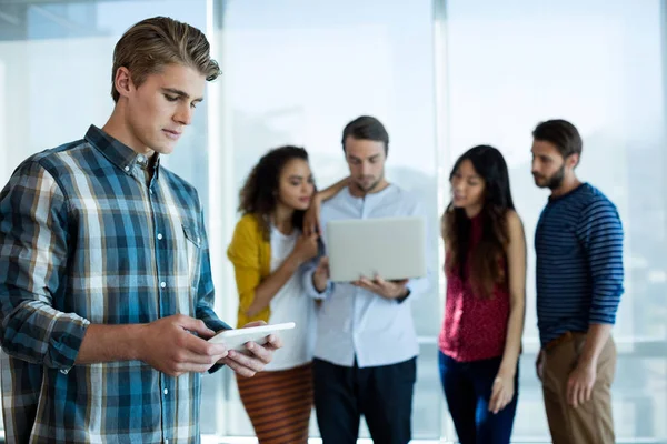 Man met digitale tablet in kantoor terwijl collega bespreken op achtergrond — Stockfoto