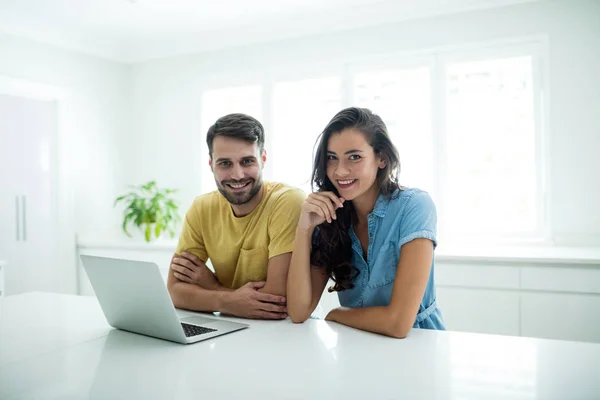 Retrato de pareja usando portátil en la cocina —  Fotos de Stock