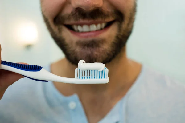Primo piano del giovane felice che tiene lo spazzolino da denti con dentifricio — Foto Stock