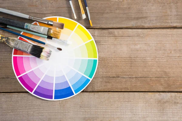 Color swatch and paintbrushes on wooden surface — Stock Photo, Image
