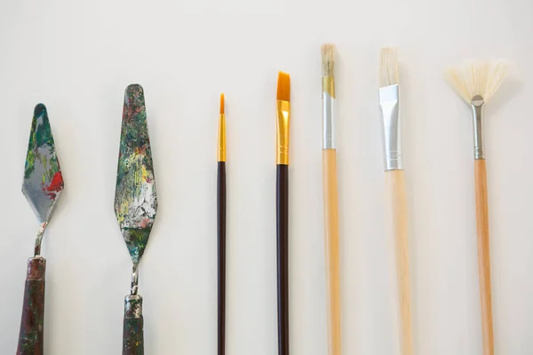 Facas de paleta e pincéis de pintura dispostos em uma fileira — Fotografia de Stock