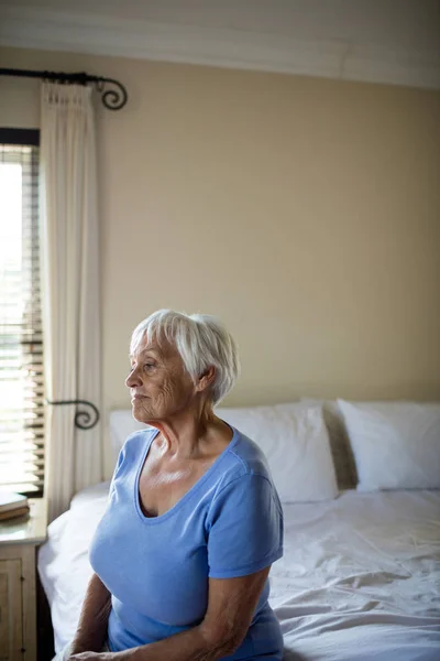 Nachdenkliche Seniorin sitzt auf Bett im Schlafzimmer — Stockfoto