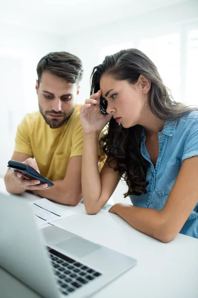 Pareja preocupada calculando sus facturas con laptop en la cocina — Foto de Stock