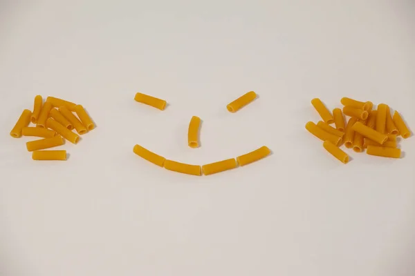 Cara sorridente feita de massa de pennette — Fotografia de Stock