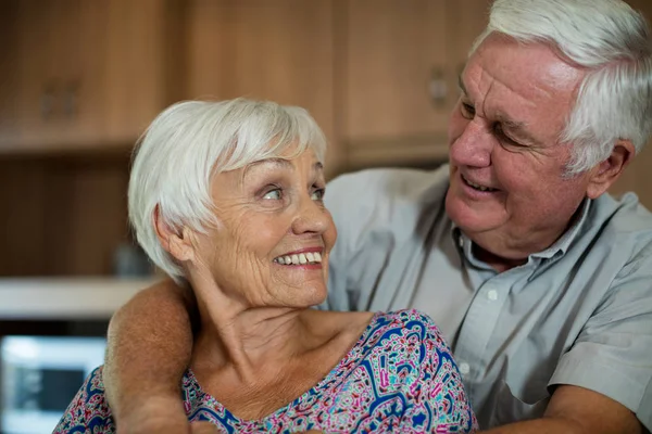 Счастливая старшая пара обнимает друг друга на кухне — стоковое фото