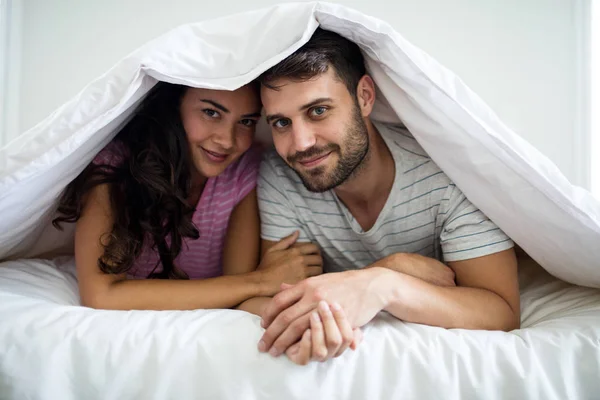 Retrato de casal feliz sob cobertor no quarto — Fotografia de Stock