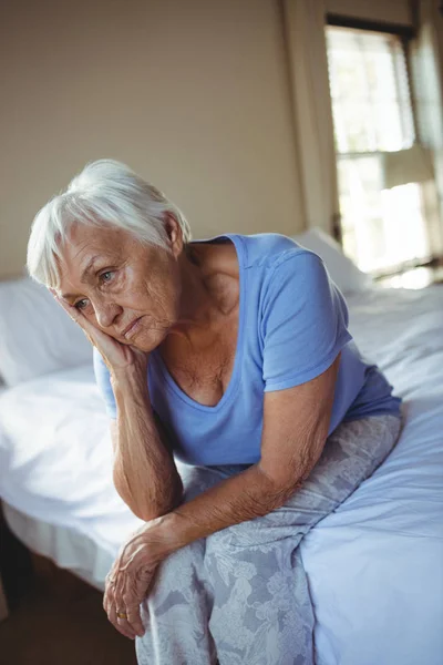 Mujer mayor preocupada sentada en la cama en el dormitorio —  Fotos de Stock