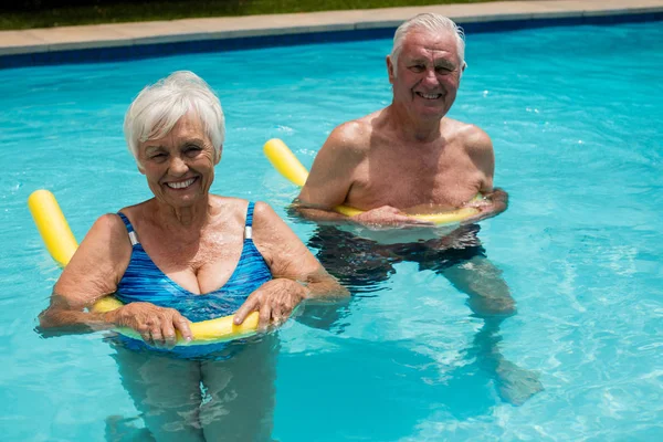 Seniorenpaar schwimmt im Pool mit aufblasbaren Schläuchen — Stockfoto