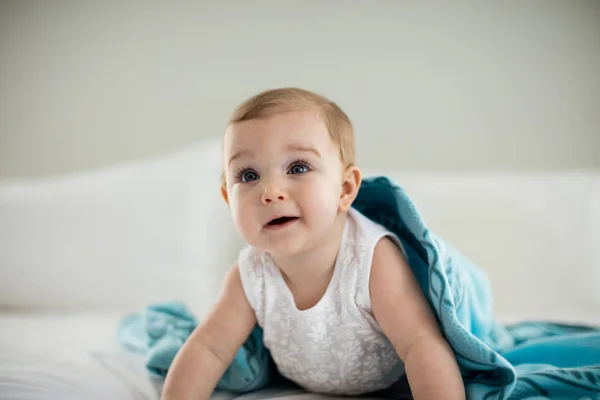 Mignon bébé fille sous la couverture sur le lit — Photo