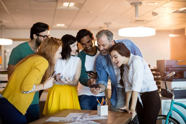 Sorrindo equipe de negócios criativa usando telefone celular no escritório — Fotografia de Stock