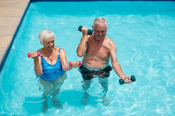 Pareja mayor haciendo ejercicio con pesas en la piscina —  Fotos de Stock