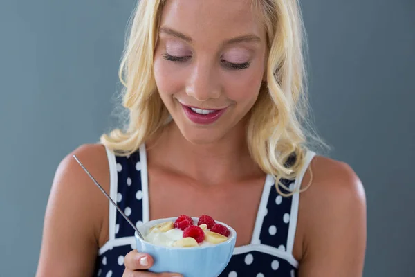 Hermosa mujer mirando ensalada de frutas en un tazón —  Fotos de Stock