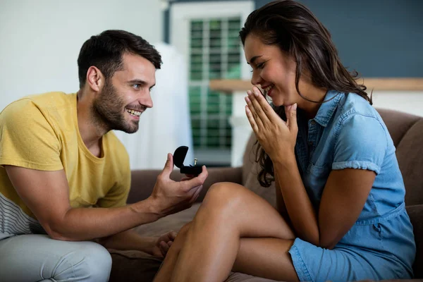 Uomo che offre un anello di fidanzamento alla donna in salotto — Foto Stock