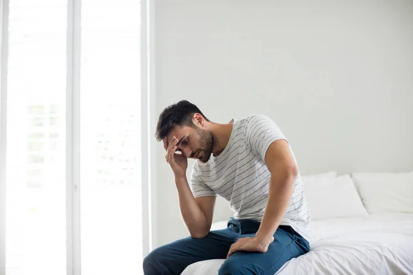 Worried man sitting in the bedroom — Stock Photo, Image