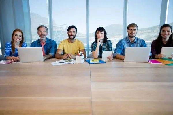 Творческая бизнес-команда, сидящая в ряд и работающая вместе в офисе — стоковое фото