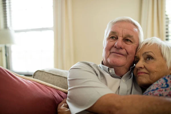 Lyckliga senior paret omfamnar varandra i vardagsrum — Stockfoto