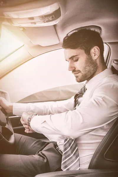 Businessman checking time while sitting on drivers seat — Stock Photo, Image