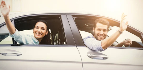 Couple souriant et agitant en voiture — Photo