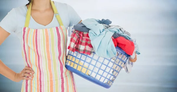 Donna in grembiule con bucato contro pannello in legno grigio sfocato — Foto Stock