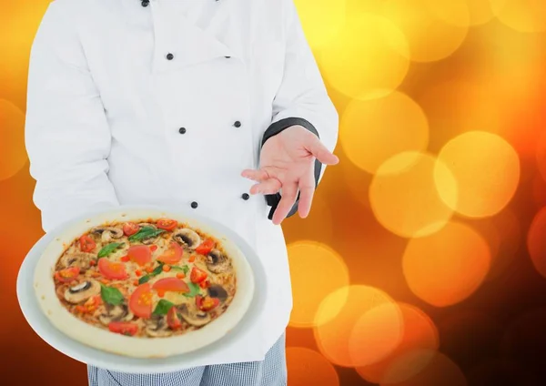 Chef com pizza contra bokeh laranja desfocado — Fotografia de Stock