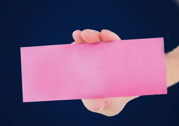 Mão com cartão em branco rosa contra fundo da marinha — Fotografia de Stock