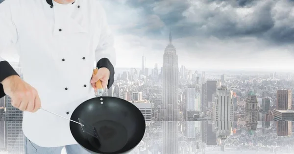 Chef com wok contra skyline embaçado — Fotografia de Stock