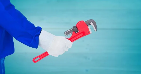 Mechanic arm with wrench against blurry blue wood panel — Stock Photo, Image