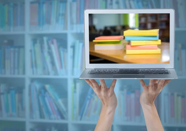 Hands with laptop showing book pile against blurry bookshelf with blue overlay — Stock Photo, Image