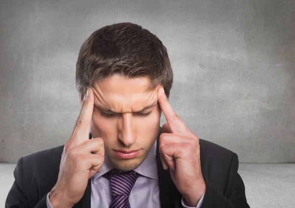 Close up of business man touching temples in grey room — Stock Photo, Image