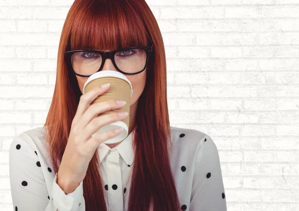 Woman with coffee cup over face against white brick wall — Stock Photo, Image