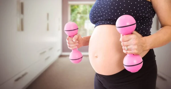 Donna incinta a metà sezione con pesi rosa in corridoio sfocato — Foto Stock