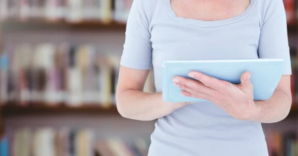 Womans hands on tablet in Library — Stock Photo, Image