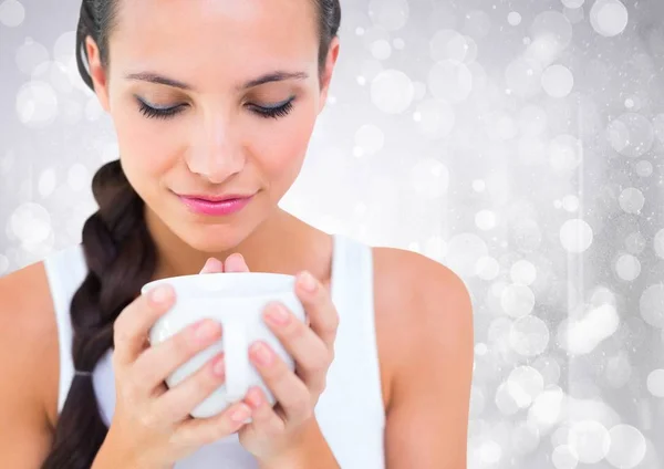 Close up of woman looking down at white cup against white bokeh — Stock Photo, Image