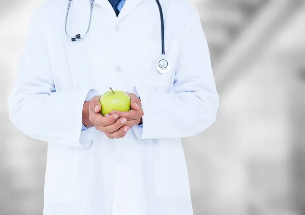 Doctor mid section with apple against blurry background — Stock Photo, Image